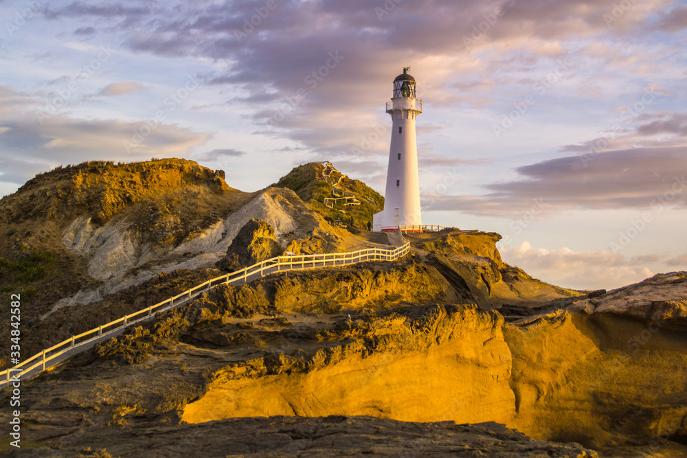 Panoramic scenic landscape view of the Castlepoint lighthouse in sunrise colours, white landmark, tourist popular attraction/destination in North Island, New Zealand. 