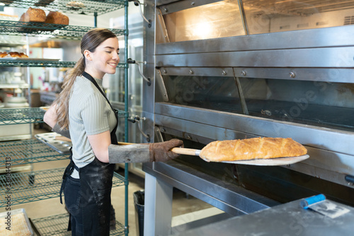 Woman taking out some bread of the oven
