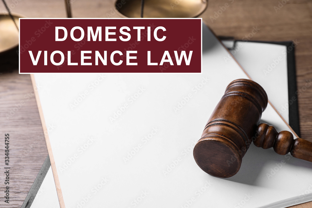 Clipboard and gavel on wooden table. Domestic violence law concept