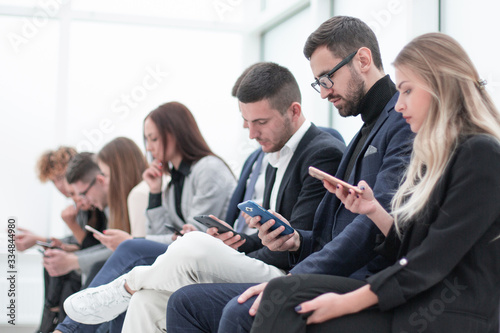 group of young business people with smartphones sitting in a row.