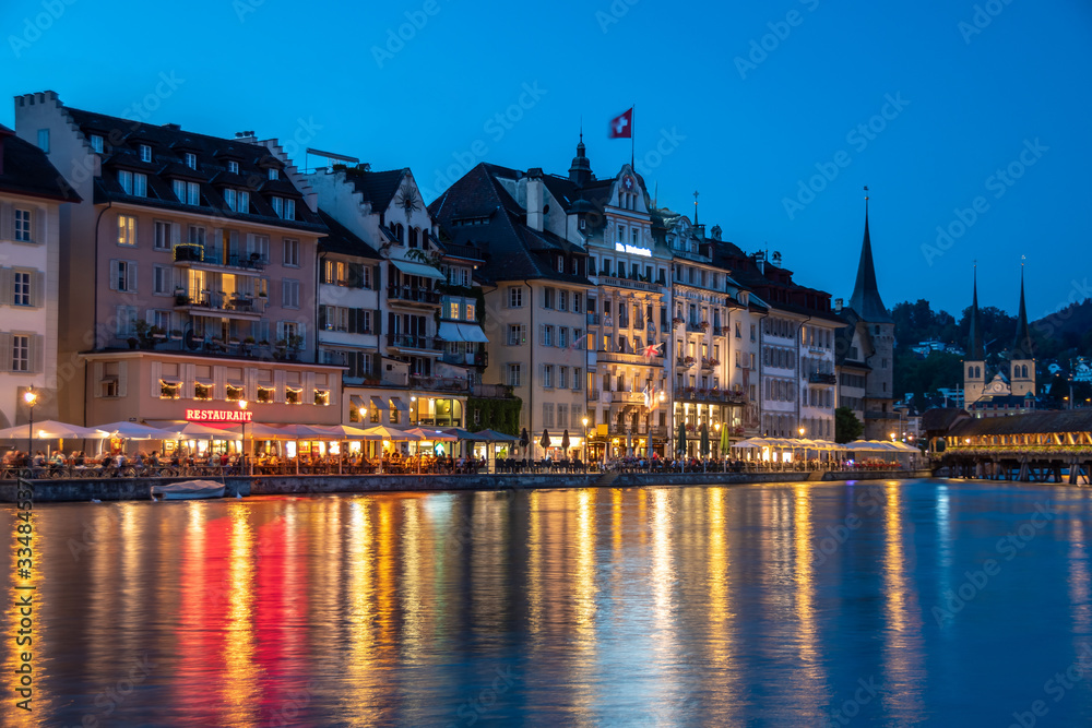 Historic city center of Lucerne, promenade and river Reuss. Lights beautifully reflected in the river. Popular touristic place with restaurants and cafes.