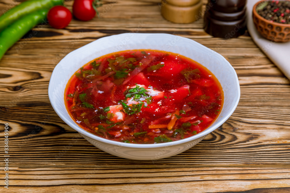 Borscht with sour cream on wooden table