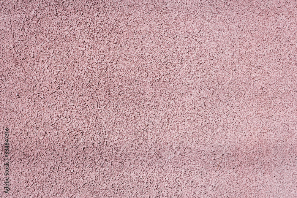 Fototapeta premium Textured wall of the building. Light pink wall.