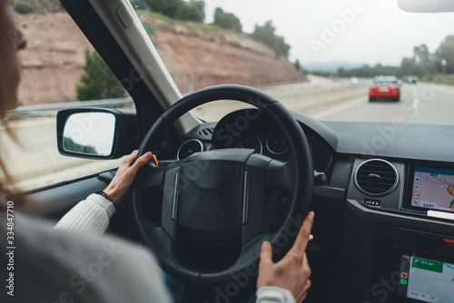 New adventures await! Back view of young female novice driver driving offroad car enjoying road trip, woman behind wheel of car driving through beautiful landscapes, Holidays outside the city concept © iana_kolesnikova