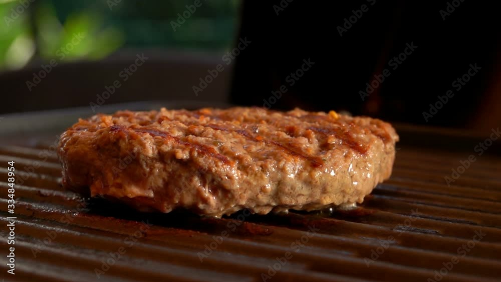 Beef cutlet for burger is frying on the grill outdoors. Ingredients for hamburger preparation on the table. Beef cutlet for burger is frying on the grill outdoors. Ingredients for hamburger preparation on the table.