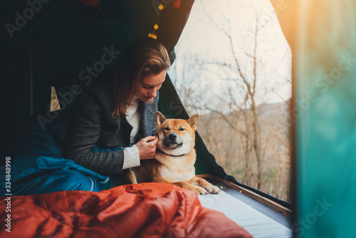 Morning in the forest. Young positive woman traveling with dog on offroad car enjoying beautiful view from a tent on a car roof, Leisure Nature Camping Lifestyle concept