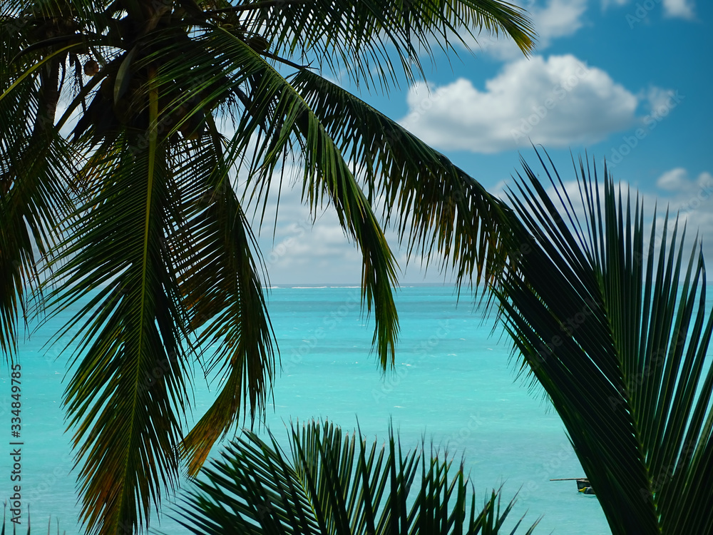 Traumkulisse Raffaello Werbung, Kokospalmen und Fernweh am weißen Strand mit türkisem Meer auf Sansibar, Fischerboote und Horizont im Hintergrund