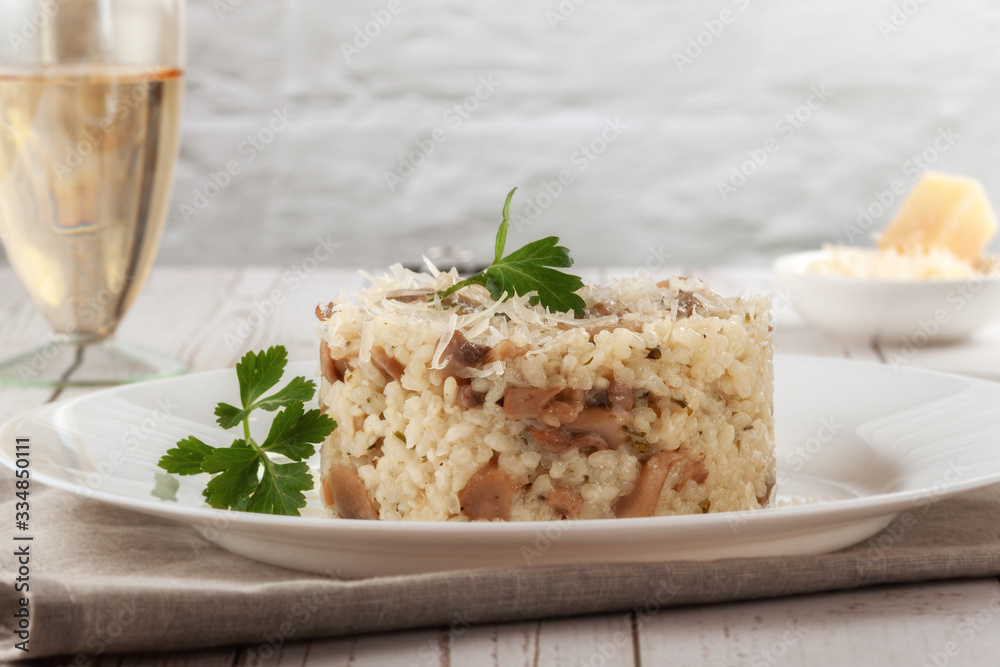 Wild mushroom risotto with parsley and parmesan on a white wooden background