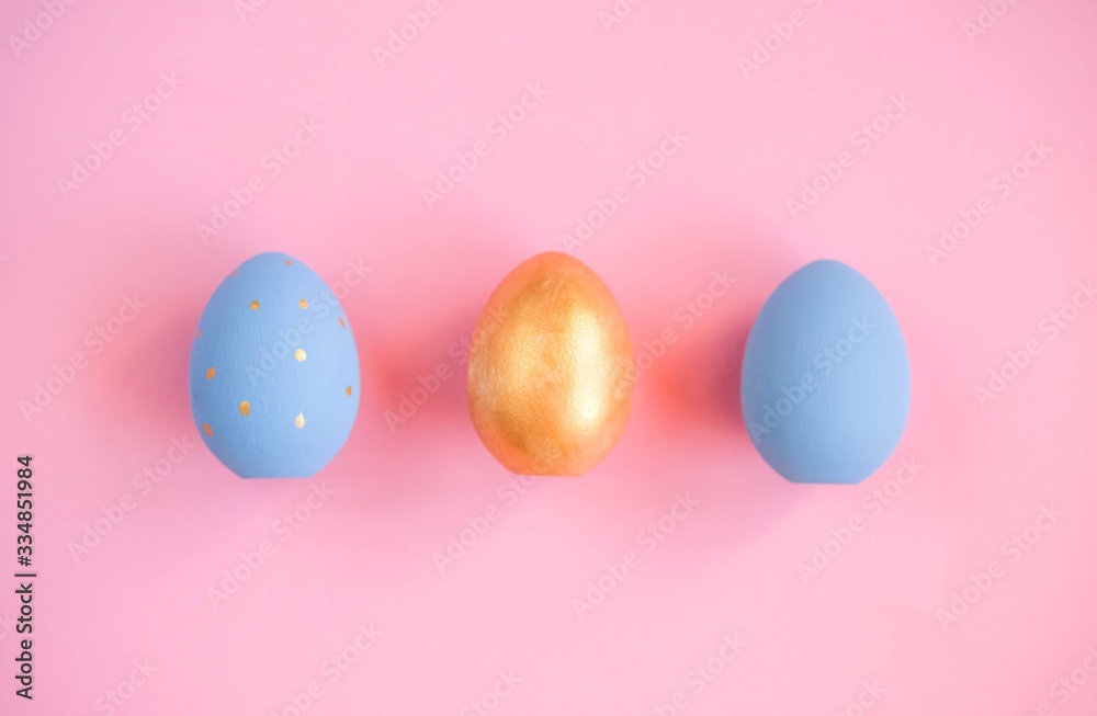 Gold and blue easter eggs on pink background.
