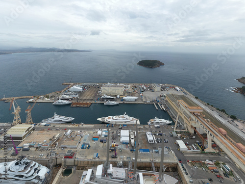 Aerial view of sea dry dock in La Ciotat city, France, the cargo crane, boats on repair, a luxury sail yacht and motor yacht, mountain is on background, shipyard photo