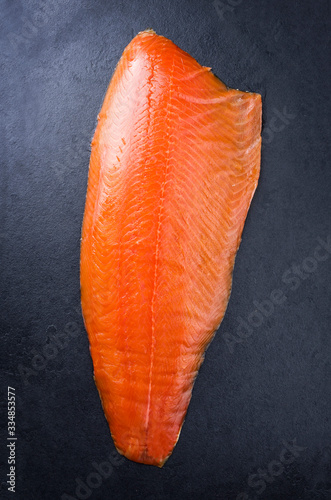 Obraz na plátne Traditional fresh smoked salmon fillet offered as top view on a black board as b