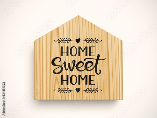 Wooden board in shape of house with phrase Home Sweet Home