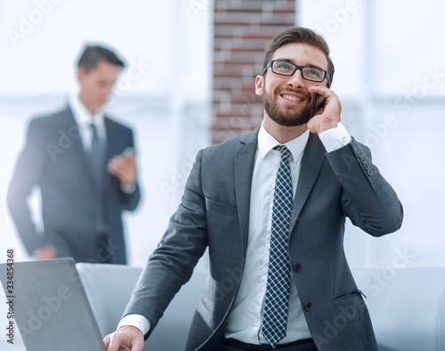 Confident young man talking on phone in office