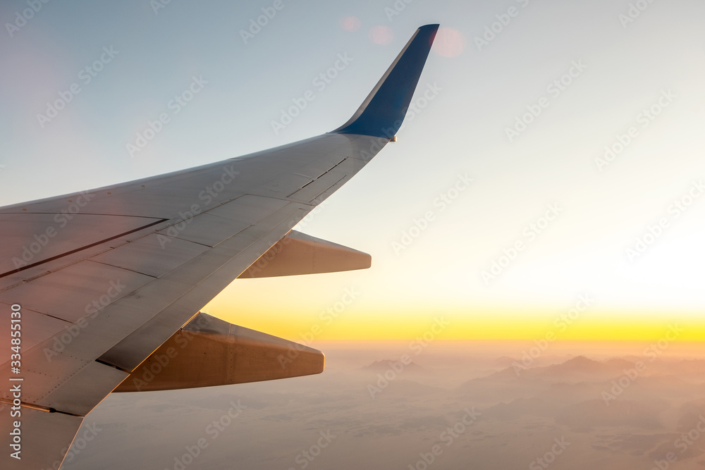 Fototapeta premium View from airplane on the aircraft white wing flying over desert landscape in sunny morning. Air travel and transportation concept.