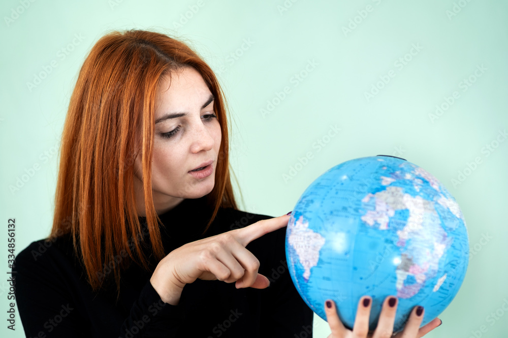 Portrait of a happy young woman holding geographic globe of the world in her hands. Travel destination and planet protection concept. Portrait of a happy young woman holding geographic globe of the world in her hands. Travel destination and planet protection concept.