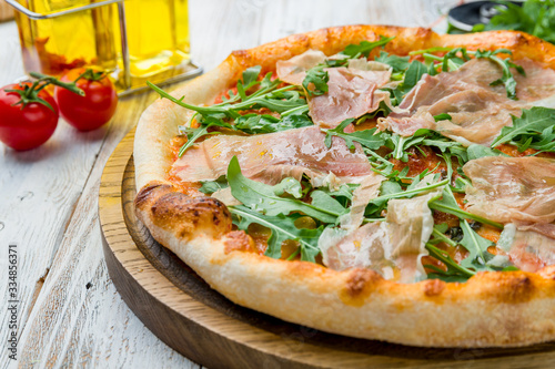 Pizza with Parma ham and arugula on white wooden table