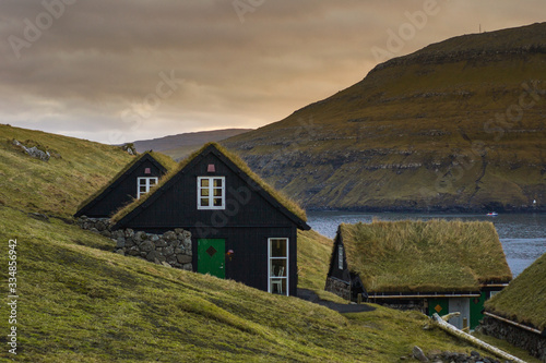Scenic landscape view of traditional historic stone wooden house/building with grass (turf) roof in Vágar Island. Tourist popular attraction/place in Faroe Islands (Denmark)