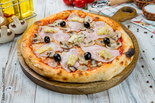 Capricciosa pizza with artichokes on white wooden table