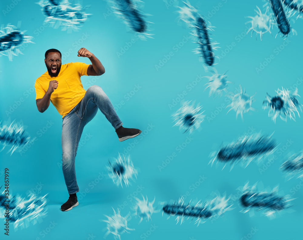 Obraz premium African-American man fighting with bare hands against viruses and bacteria on cyan background