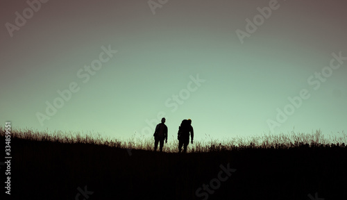 two friends travellers on hill during sunset silhouette