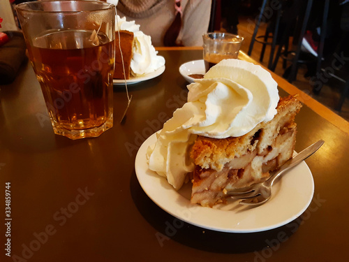 Photography high Dutch apple pie with plenty of whipped cream on a brown wooden table with a