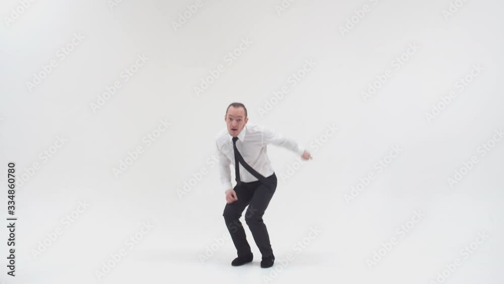 The businessman jumps and points his index fingers at the distance, on a white background. A male breakdancer in office clothes dances the lower break with his feet and jumps up pointing his fingers The businessman jumps and points his index fingers at the distance, on a white background. A male breakdancer in office clothes dances the lower break with his feet and jumps up pointing his fingers