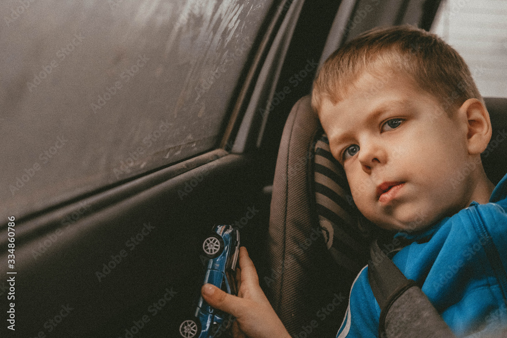 a boy sitting in a car seat in a car with a toy