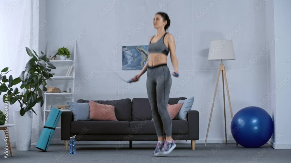 Sportswoman training with skipping rope in living room Sportswoman training with skipping rope in living room
