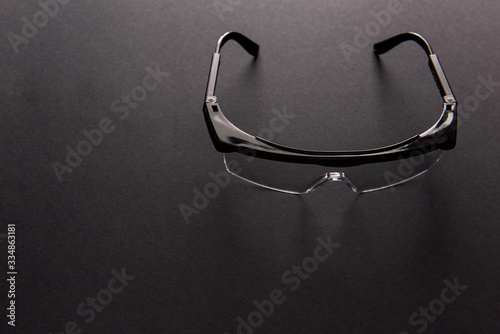 Transparent safety goggles on dark gray background photo