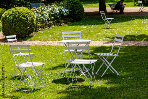 White chairs and a table stand on the lawn in the Park
