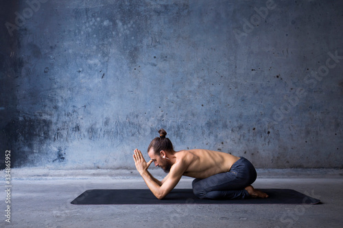 Man practicing yoga and meditation in a urban background