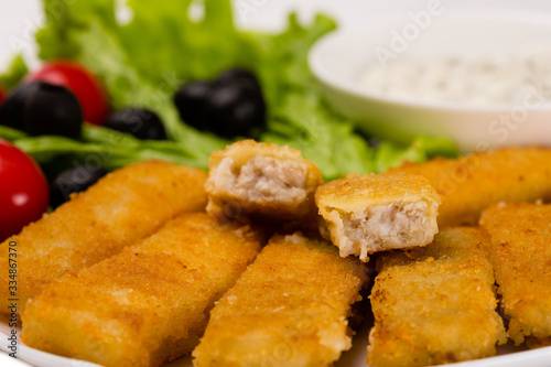 Fried fish fingers with vegetables close up