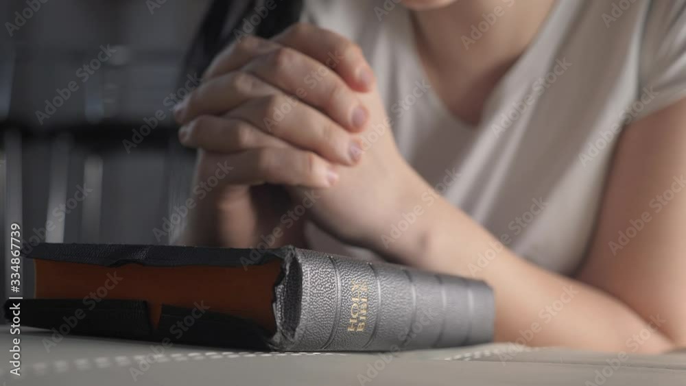 girl praying indoors at bedtime on bible. religion concept evening prayer woman brunette hands on bible praying lifestyle by bed girl praying indoors at bedtime on bible. religion concept evening prayer woman brunette hands on bible praying lifestyle by bed