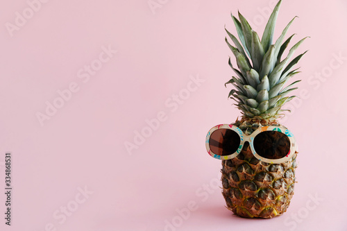 Fresh pineapple in sunglasses stands on a pink background. The concept of rest, travel, vacation, relaxation. Save the space. Horizontal orientation