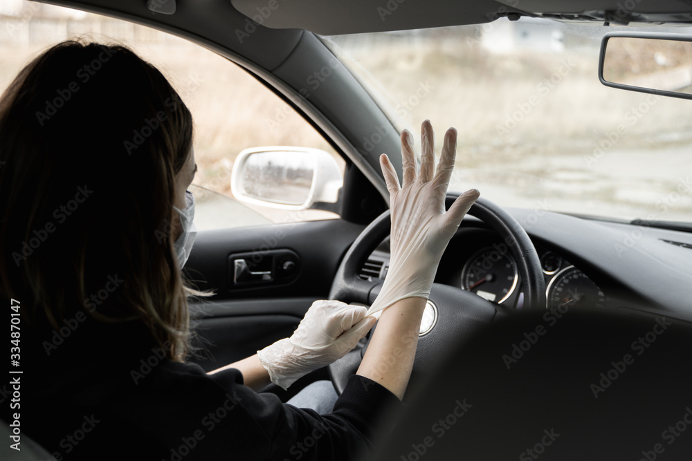 Woman in protective medical mask is wearing rubber gloves for protect himself from bacteria virus while planning to drive. Protective mask while quarantine, pandemic, covid 19, coronavirus, infection.
