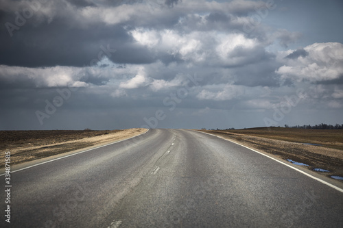 Natural landscape with an asphalt road leading towards thunderclouds