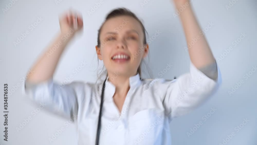 Funny doctor woman in a white coat with a stethoscope dancing in a hospital Funny doctor woman in a white coat with a stethoscope dancing in a hospital