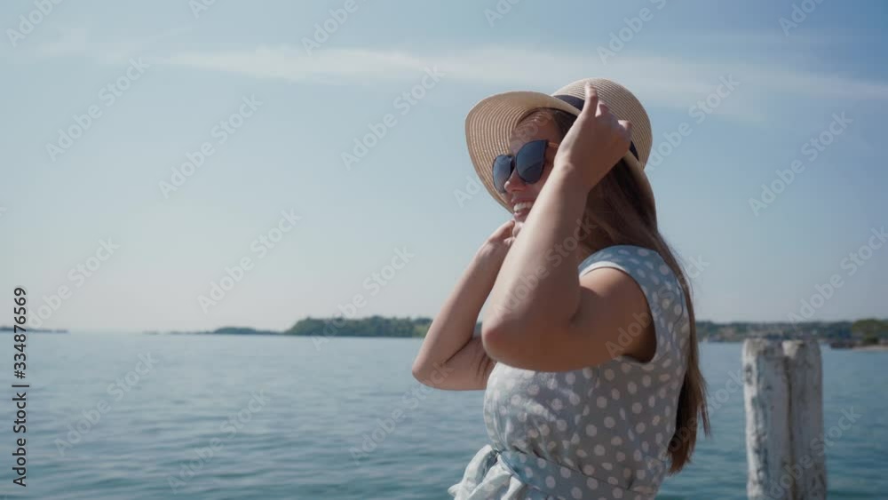 Woman in sunglasses takes off straw hat from camera, puts it on head cheerfully Woman in sunglasses takes off straw hat from camera, puts it on head cheerfully