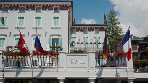 Hotel sign on facade of building, flying flags of different countries, sunny day