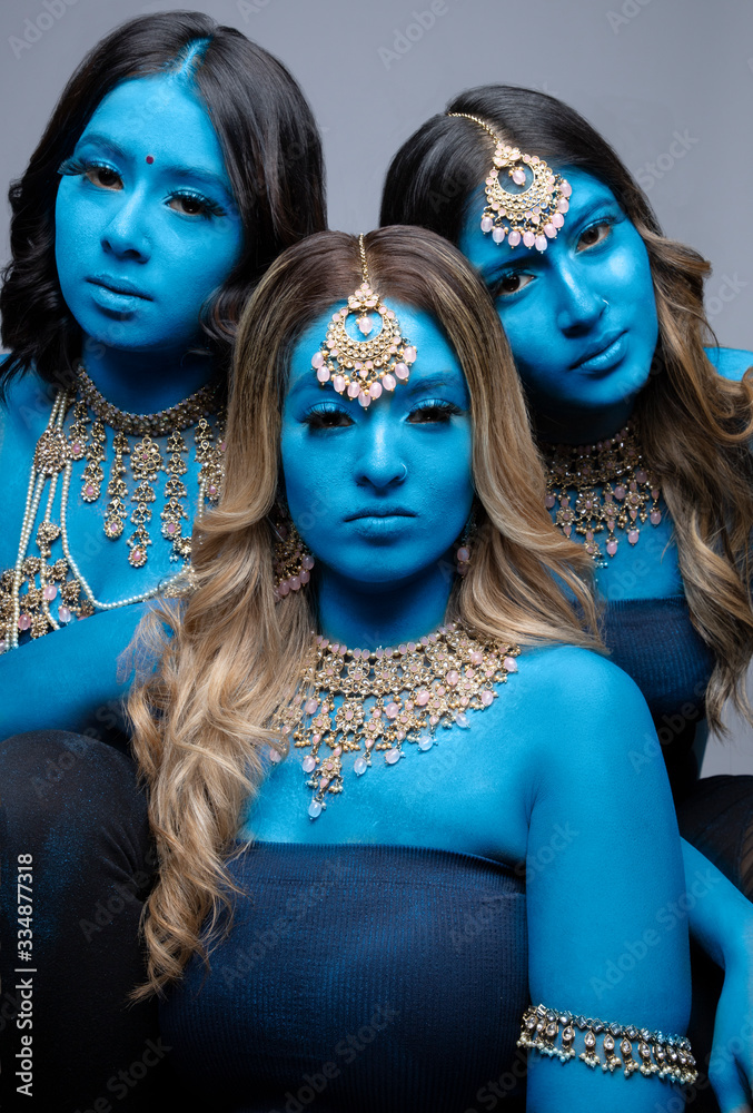 Thee women with blue body paint wearing gold jewelry Stock Photo