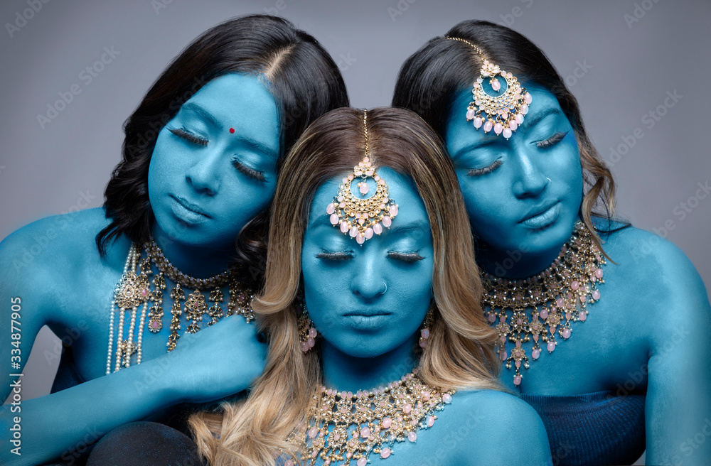 Thee women with blue body paint wearing gold jewelry Stock Photo