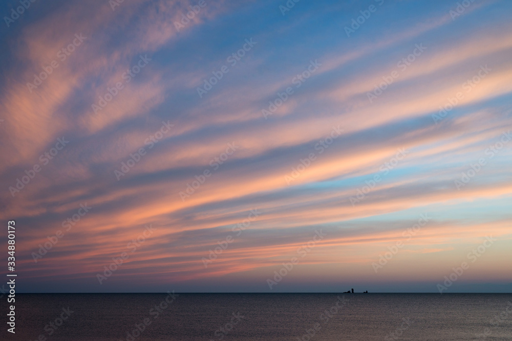 Picturesque sunset over the sea with distant rocks