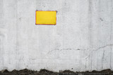An empty yellow sign on an old cracked concrete wall