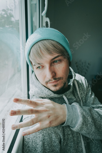 Young man alone in his home near a window