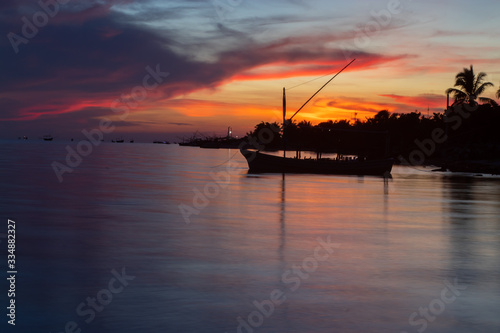 Sunset in the beach with a fishing boats shadow