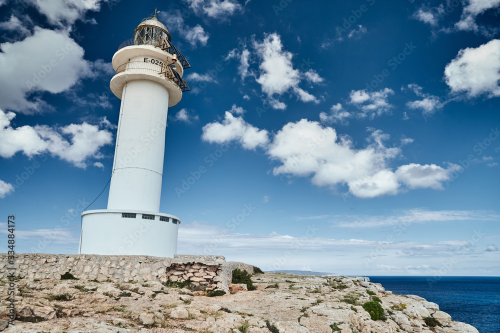 Lighthouse on the Formentera island, Spain, the blue sky with white clouds, without people, rocks, stones, sunny weather