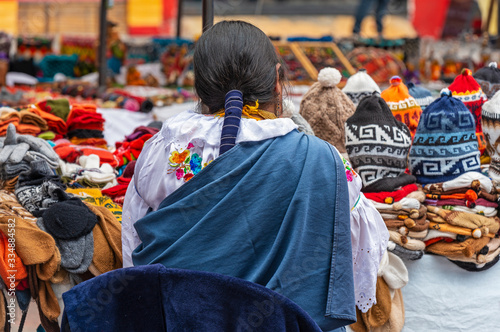 Indigenous women in traditional clothing and hairstyle by her market stall on the sunday art and craft market of Otavalo, North of Quito, Ecuador. photo