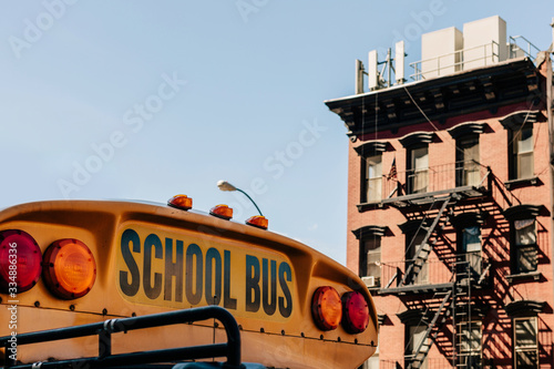 Detail of the text school bus on the front of a bus and in the background a typical new york city building. America