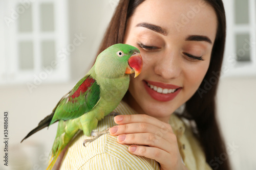 Fotografiet Young woman with Alexandrine parakeet indoors, closeup. Cute pet