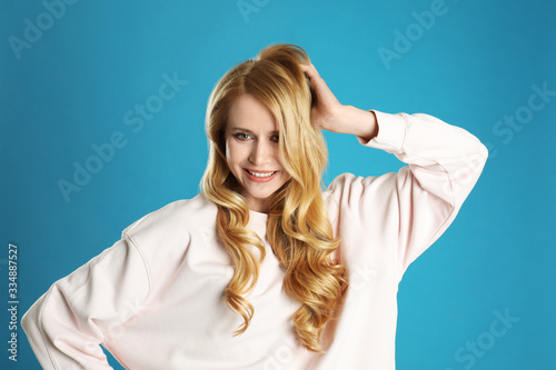 Portrait of beautiful young woman with dyed long hair on blue background